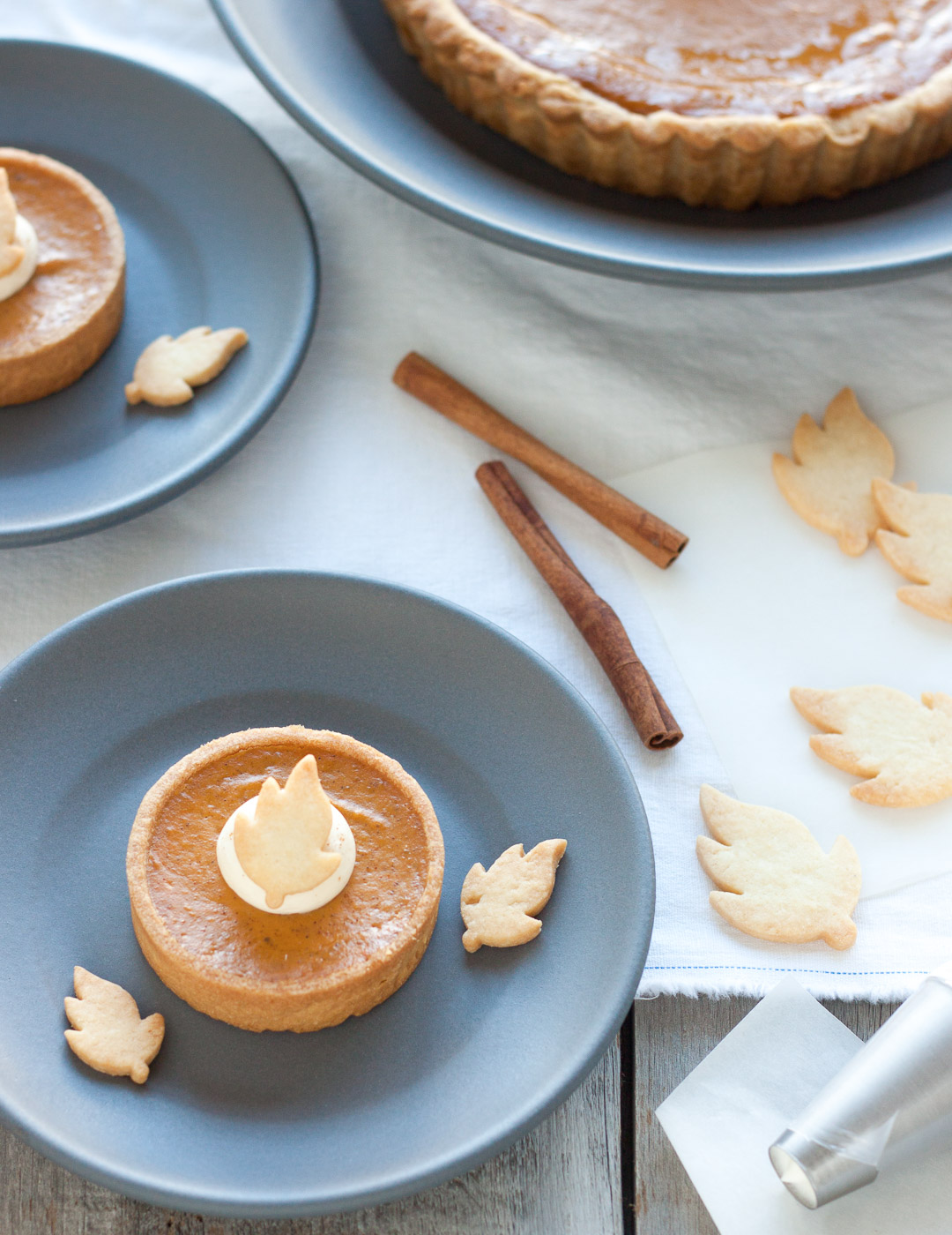 Homemade Thanksgiving pumpkin pie with a buttery crust, smooth spiced pumpkin filling, topped with whipped cream and shortbread cookie leaves