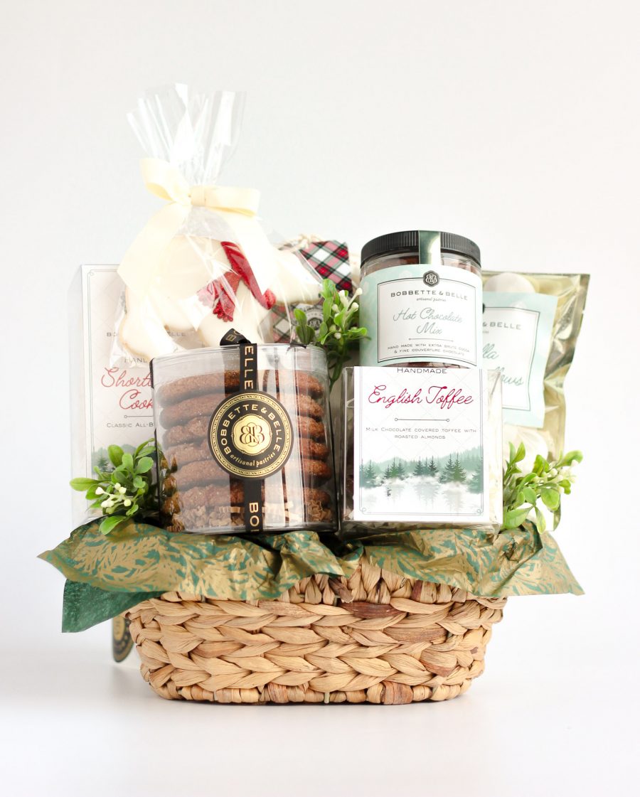 Holiday Gift Basket with Gourmet Cookies and Festive Treats A woven holiday gift basket filled with gourmet treats, including ginger cookies, caramel corn, English toffee, shortbread, hot chocolate, marshmallows, and a decorative polar bear sugar cookie.