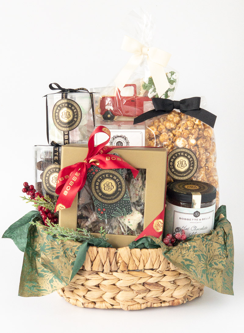 Deluxe Holiday Gift Basket – Gourmet Treats and Festive Packaging A beautifully arranged holiday gift basket featuring gourmet treats, including caramel popcorn, chocolates, cookies, and preserves, wrapped with festive ribbons and accents.