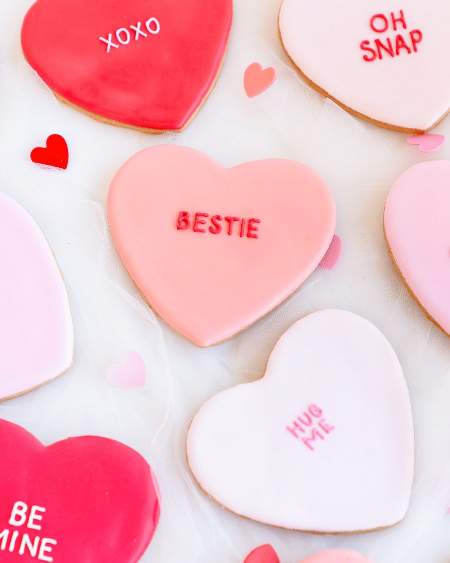 Valentine’s Conversation Heart Cookies – Assorted Sayings Heart-shaped sugar cookies with fondant icing and Valentine’s messages like XOXO, YAAS, and BE MINE.